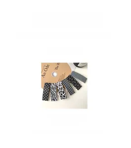 Close-up of rectangular hair clips with checkerboard, leopard, and polka dot fabric patterns