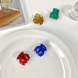 Mini pumpkin hair claws in four vibrant candy colors on a decorative white tray