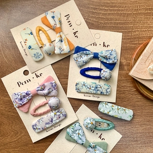 Floral bow hair clip set for girls with Korean style fabric patterns on wood background