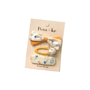 Three-piece floral hair clip set with butterfly bow and button patterns on cardboard