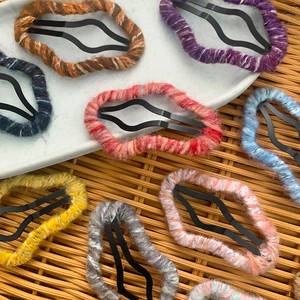 Handmade knitted wool cloud hair clips set in various colors on a rustic tray