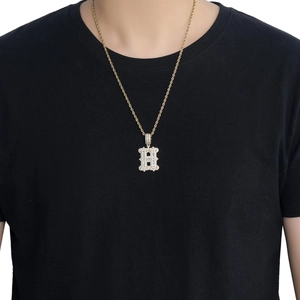 Détail du collier avec pendentif lettre H dorée orné de cristaux blancs et chaîne torsadée