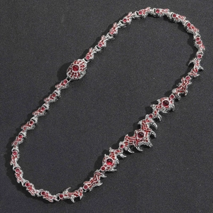 Detailed view of hip hop thorn necklace with red crystal eyes on black texture