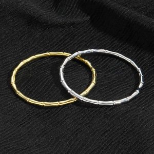 Minimalist bamboo joint bangles in gold and silver finish on black textured background