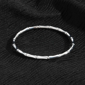 Macro detail of silver bamboo joint bracelet with polished segments on black fabric