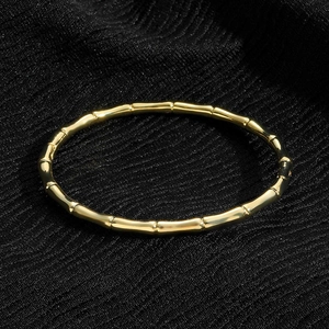 Close-up of golden bamboo joint bracelet with polished finish on black fabric