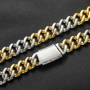 Close-up of 20mm two-tone Cuban link chain with a polished silver box clasp on black texture