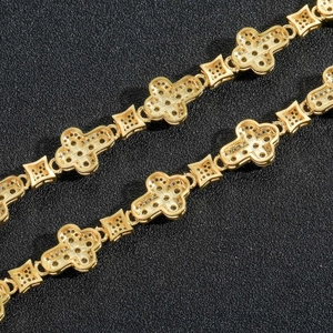 Macro detail of gold-plated hip-hop bracelet featuring iced-out cross links and zircon pavé