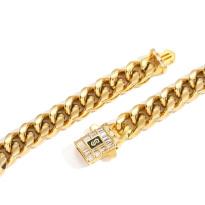 Détail macro de la chaîne cubaine dorée avec boucle sertie de zircons et logo S