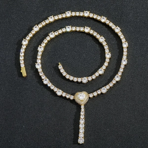 Macro shot of gold tennis chain necklace with zircon heart pendant and fringe tassel