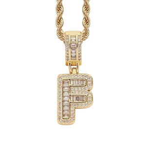 Close-up of golden letter F pendant with baguette-cut diamonds on a rope chain