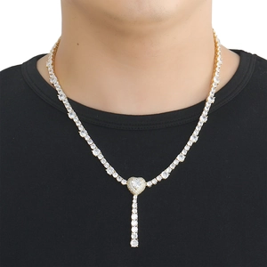 Close-up of gold plated tennis chain featuring a micro-pave heart pendant and tassels