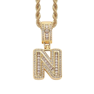Detailed close-up of golden letter N pendant with baguette and round cut zircons