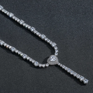 Macro shot of silver tennis chain necklace with micro-pave heart pendant on black display