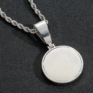 Macro shot of silver polished round pendant with classic rope chain on black texture