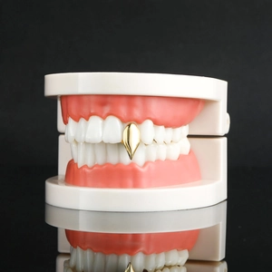 Gepolijste vergulde vampiertand grillz getoond op een model van een enkele tand
