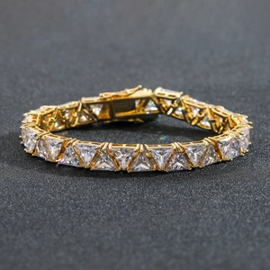 Macro shot of gold tennis bracelet featuring triangle cut zircons and a secure fold-over clasp