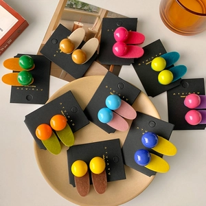 Colorful candy bead hair clips on display cards with aesthetic props and warm lighting