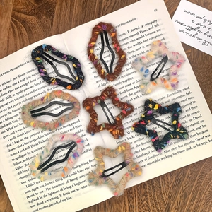 Barrettes à cheveux étoilées en laine colorée tricotée sur un fond de livre ancien