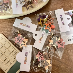 Close-up of colorful star hair clips in Morandi tones with floral accents on wood