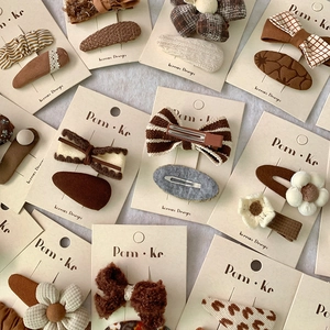 Korean style floral and bow hair clips set in creamy brown colors on white plush background