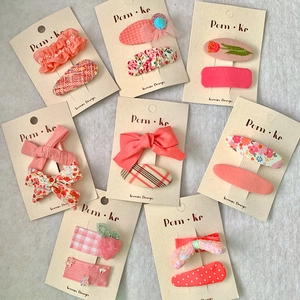 Pink fabric bow hair clips for girls featuring embroidery and sequins on card display
