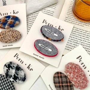 Two-piece vintage wool tweed oval hair clips set with plaid patterns on a white display card