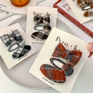 Three-piece checkered fabric bow hair clips for girls set on a decorative plate