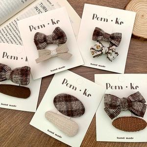 Detail of plaid and floral fabric bow hair clips in earthy tones on a rustic wooden table