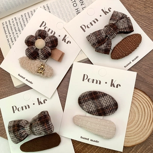 Detailed view of plaid fabric and flower hair clips in warm brown autumn tones