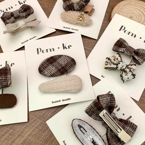 Close-up of brown plaid and corduroy hair clips on branded white display cards