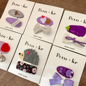 Handmade purple cartoon animal hair clips with embroidery and lace on a wooden background
