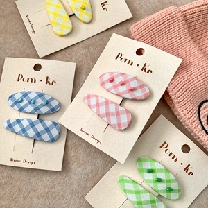 Set of four colorful plaid fabric hair clips for girls on display cards with soft background