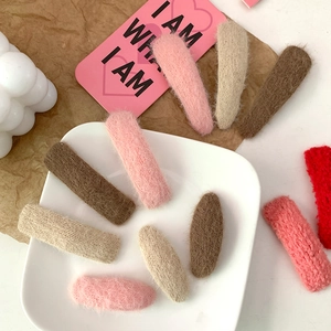 Plush faux fur hair clips in various colors and shapes on a decorative plate