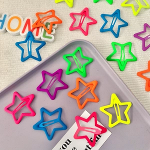 Fluorescent star shaped hair clips in various bright colors on a purple tray