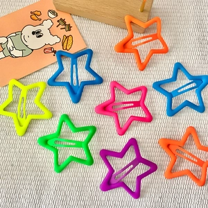 Vibrant neon star-shaped hair clips for girls in matte finish on a white fabric background