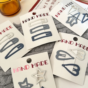 Minimalist matte hair clips set in star and heart shapes on a grey knit background