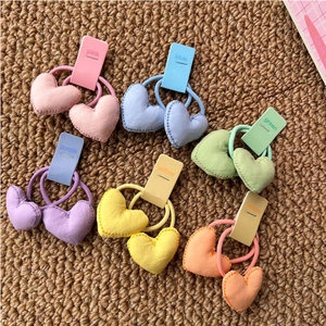 Vue détaillée d'élastiques à cheveux en peluche cœur macaron sur fond texturé