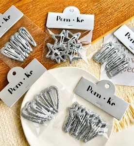 Detailed view of silver glitter hair clips in star and heart shapes on display card
