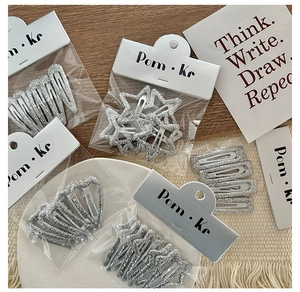 Detail view of sparkly silver glitter hair clips in star and heart shapes on display card