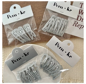 Close-up of sparkling silver glitter BB hair clips in various shapes on display card