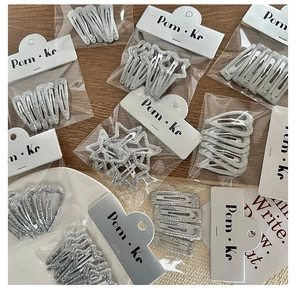 Detail showing assorted glittery silver star and heart hair clips in retail packaging