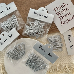 Sparkly silver glitter hair clips set featuring star and heart shapes on white tray