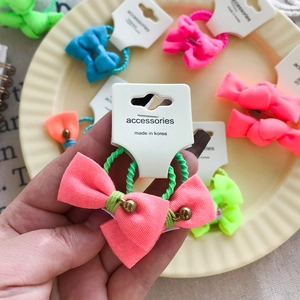 Détail de chouchous à nœuds colorés avec clochettes sur une carte de présentation