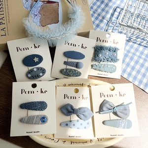 Blue lace bow hair clip set with pearls and rhinestones on decorative display