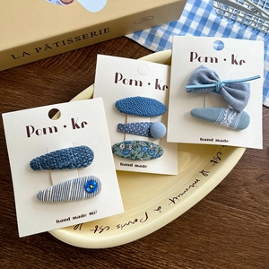 Close-up of blue fabric bow hair clips with polka dots and floral patterns on display card
