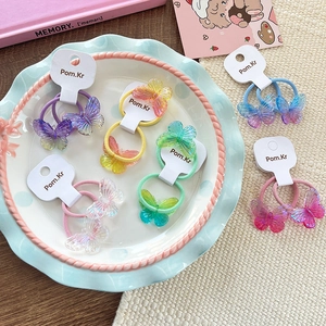 Detail of gradient butterfly hair ties in various colors on a ceramic plate for girls