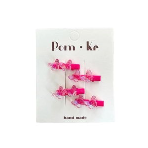 Set of four gradient pink bow hair clips with glitter details on a white display card