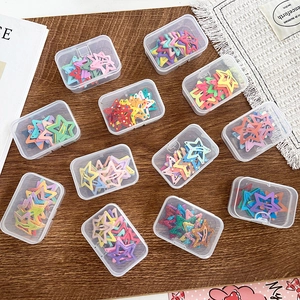 Colorful star-shaped hair clips set in transparent gift boxes on wood background