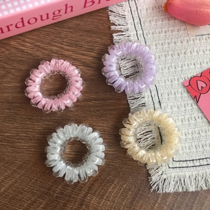 Set of four colorful high-elastic spiral telephone wire hair ties on a wooden surface